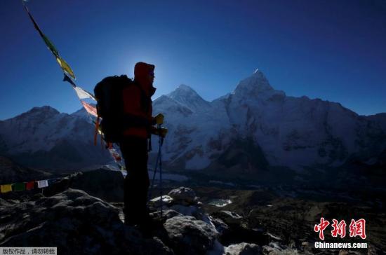 资料图：一名登山者站在珠峰前。