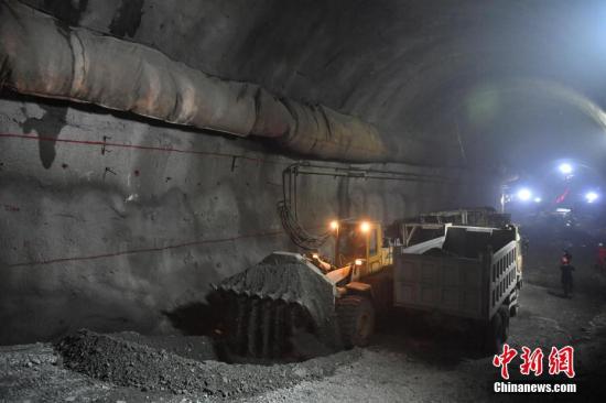 6月17日，隧道内挖机正进行出渣作业。当日，正在建设中的中（国）老（挝）铁路国内段新平隧道四个辅助坑道正洞同步实现贯通，标志着中老铁路国内段关键控制性工程建设取得重要进展。据了解，位于云南省新平县境内的新平隧道共穿越7条断裂破碎带，岩体破碎、涌水、突泥频发，为国家I级高风险隧道，是全线的“咽喉”工程。中老铁路是中国“一带一路”倡议提出后，首条以中国为主投资建设、全线采用中国技术标准，使用中国设备并与中国铁路网直接联通的国际铁路。线路全长1000多公里。<a target='_blank' href='http://www.chinanews.com/'>中新社</a>记者 任东 摄