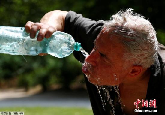 当地时间6月24日，比利时布鲁塞尔的一个公园内，一名男子在用冰水解暑。