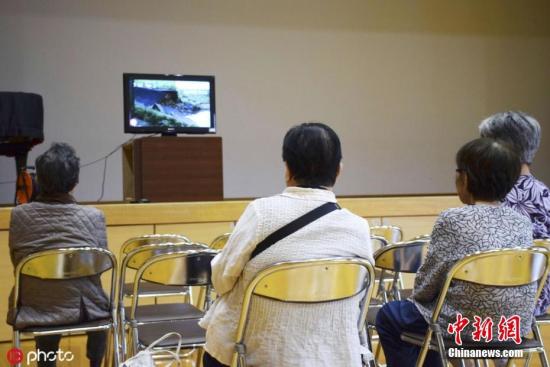 当地时间2019年7月4日，日本熊本市，几位居民坐在临时疏散中心内观看电视报道。 图片来源：ICphoto