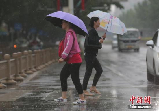 资料图：民众冒雨在街头出行。<a target='_blank' href='http://www.chinanews.com/'>中新社</a>记者 杨可佳 摄