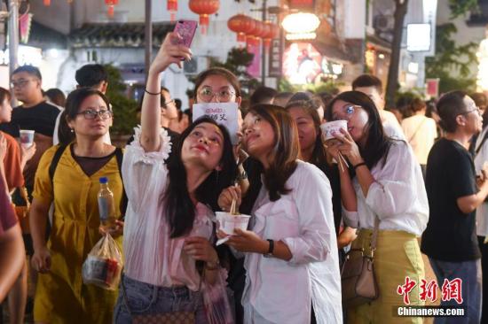 市民在湖南省长沙市街头手持当地美食合影。/p中新社记者 杨华峰 摄