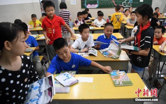 资料图：2019年9月1日，福州中山小学学生正在为同学发放教材。张斌 摄