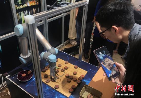 9月24日，“伟大历程 辉煌成就——庆祝中华人民共和国成立70周年大型成就展”在北京展览馆向公众开放。图为参观者与智能机器人比拼象棋技艺。中新社记者 侯宇 摄