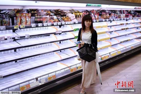 面对风暴来袭，日本民众几天前就开始采购电池和防灾用品。日本各地多家超市更是出现人们忙着囤积食物和日用品的景象。图为日本超市被半空的货架。