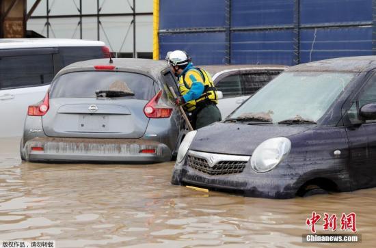 当地时间10月14日，台风“海贝思”造成日本长野县洪水泛滥，当地紧急开展救援行动。图为救援人员对被洪水淹没车辆逐一检查。