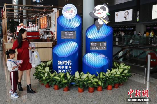 11月3日，第二届中国国际进口博览会即将开幕，上海的各个重要场所进博会氛围浓厚。图为旅客从虹桥机场T2航站楼进博会景观前走过。殷立勤 摄