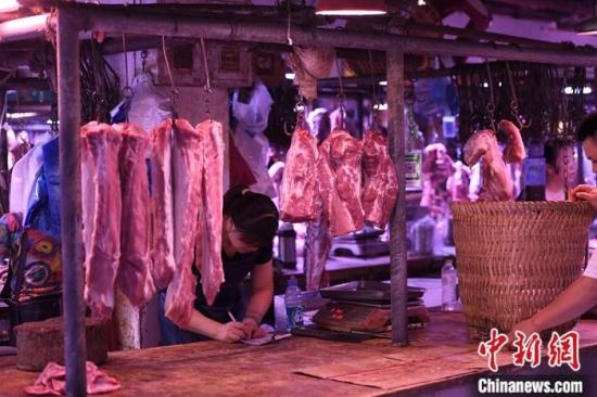 资料图为一农贸市场内的商家挂满充足的猪肉。/p中新社记者 陈超 摄