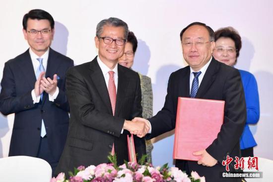 11月21日，香港特区财政司司长陈茂波(前排左)与商务部副部长王炳南(前排右)签署《修订协议》后握手庆祝。/p中新社记者 李志华 摄