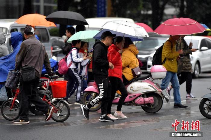 资料图：降雨天气中，出行的市民都穿起了厚实的外衣。张斌 摄