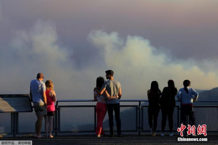 资料图：澳大利亚新南威尔士州卡托姆巴瞭望台上，人们看着绿荆溪大火的浓烟。