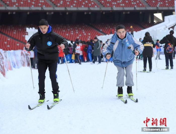 北京市中小学生奥林匹克冬令营在国家体育场“鸟巢”进行，来自北京市107所奥林匹克教育示范学校的近3000余名中小学生参与其中。活动现场设置了打雪仗、雪地对对碰、超级雪圈等趣味性游戏，以及自由滑雪、模拟冬季两项、滑冰、模拟冰壶等冰雪运动项目。图为来自北京市昌平二中的维吾尔族学生帕尔哈提(右)和希尔扎提练习滑雪。<a target='_blank' href='http://www.chinanews.com/'>中新社</a>记者 贾天勇 摄