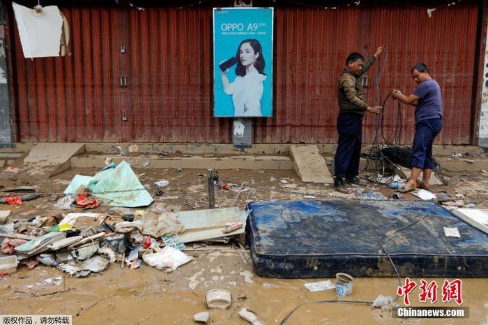 当地时间1月3日，印度尼西亚西爪哇省Bekasi街头一片泥泞。图为工作人员在遍地狼藉的街头修复电缆。
