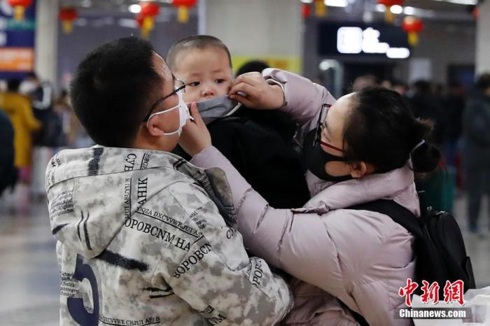 1月23日，北京西火车站迎春运客流高峰，旅客佩戴口罩乘车。中新社记者 韩海丹 摄