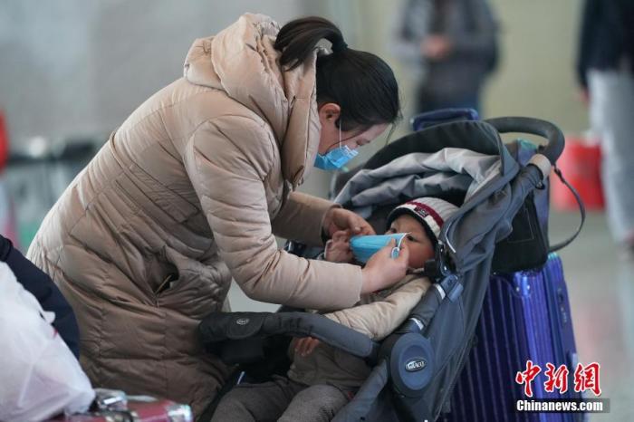 资料图：安徽蚌埠南站内，一名旅客为儿童佩戴口罩。<a target='_blank' href='http://www.chinanews.com/'>中新社</a>记者 张兴龙 摄