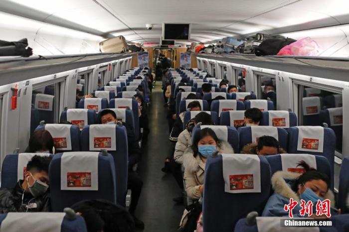 资料图：1月30日，在阜阳西站至上海虹桥的G9471次列车车厢内，佩戴口罩的旅客。/p中新社记者 殷立勤 摄