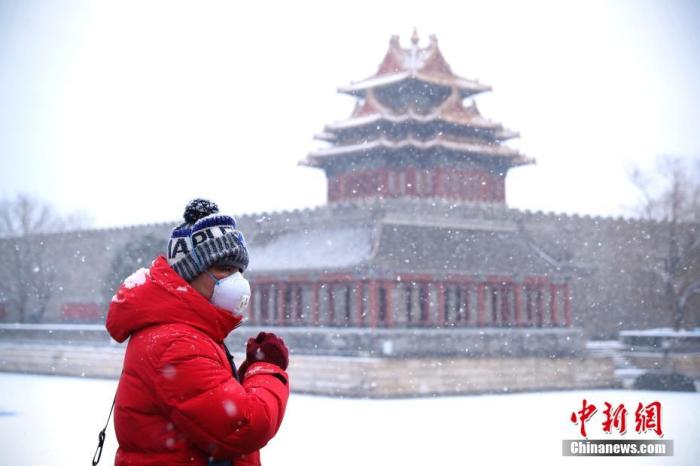 2月5日，民众戴着口罩欣赏雪中的北京故宫角楼。当日，北京迎来鼠年第二场降雪，也是立春后的第一场雪。<a target='_blank' href='http://www.chinanews.com/'>中新社</a>记者 刘震 摄