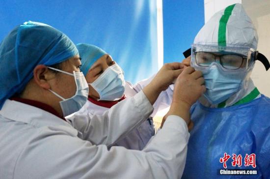 资料图：医务人员在同事的帮助下穿戴防护服。<a target='_blank' href='http://www.chinanews.com/'>中新社</a>记者 欧惠兰 摄