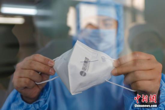 An employee of Harbin Pharmaceutical Group displays the medical mask they have produced, in Harbin, Heilongjiang Province, Feb. 10, 2020.  (File photo/China News Service)