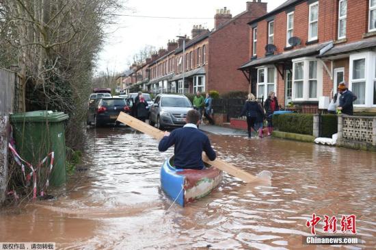 图为当地时间2月17日，风暴“丹尼斯”过后，英格兰西部怀伊罗斯的怀伊河决堤，一名男子用木板在洪水上划船出行。