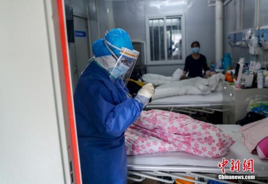 火神山医院感染二科一病区的隔离病房内医护人员为患者进行身体检查。<a target='_blank' href='http://www.chinanews.com/'>中新社</a>记者 张畅 摄