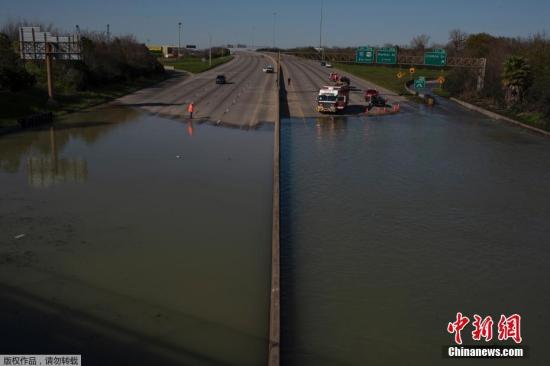 当地时间2月27日，美国休斯敦城东区的地下水管主管道破裂，导致水溢出漫延到公路上。图为救援人员封锁道路并对被困车辆人员实施救助。