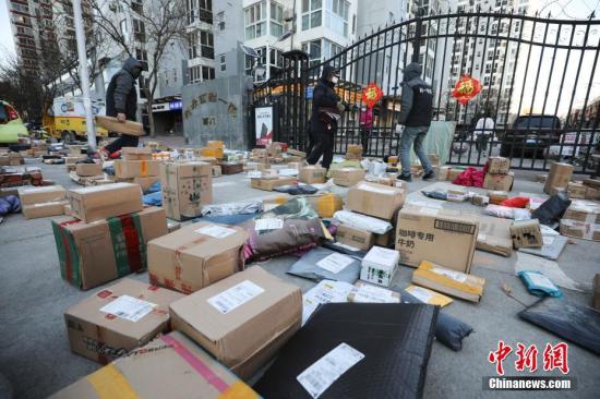 3月3日，北京朝阳区一小区门口，快递员为居民查找快递物品。受疫情影响，许多市民“宅”在家中，网购成为消费主流，而线上下单量也随之呈现爆发式增长，不少小区门口出现快递物品扎堆的现象。中新社记者 赵隽 摄