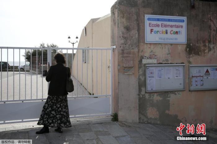 法国新冠肺炎确诊病例当地时间12日仍在快速增加，达到2876例，死亡病例增至61例。图为一名妇女站在法国地中海科西嘉岛一所封闭的学校大门前。