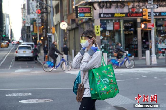 当地时间3月21日，美国纽约时代广场一位行人防护严密。据美国约翰斯·霍普金斯大学发布统计数据，截至21日傍晚，美国累计新冠肺炎确诊病例已经超过25000例，其中纽约州确诊病例超过10000例。<a target='_blank' href='http://www.chinanews.com/'>中新社</a>记者 廖攀 摄