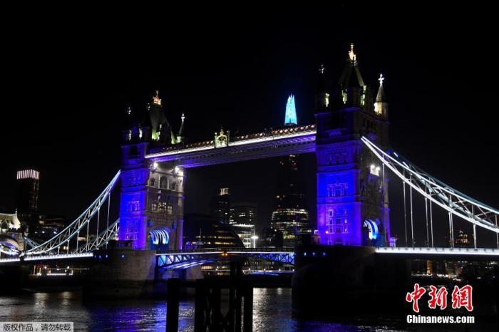 当地时间3月26日，为了支持抗击新冠肺炎的医疗人员，伦敦地标亮起蓝色灯光。图为伦敦塔桥和碎片大厦在夜晚亮起蓝色灯光。