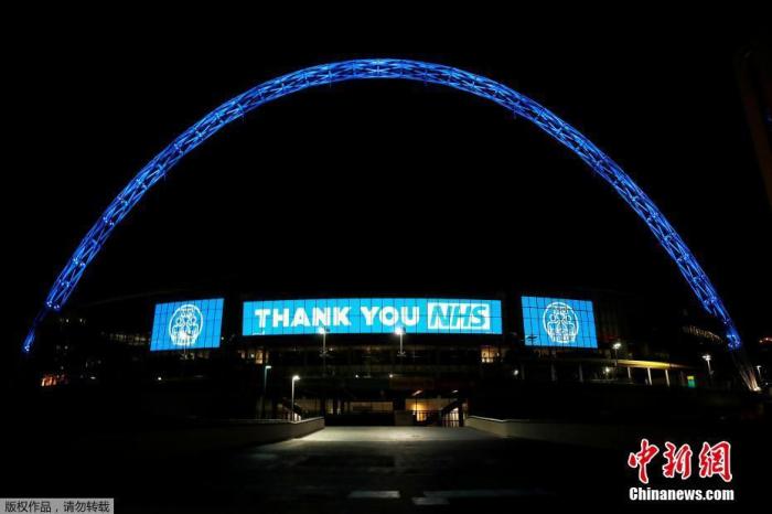 当地时间3月26日，为了支持抗击新冠肺炎的医疗人员，伦敦地标亮起蓝色灯光。图为温布利球场打出“感谢你”的字样。