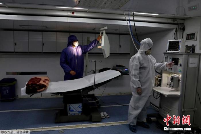 当地时间3月26日，伊朗德黑兰国际展览中心，穿防护服的工作人员在操作医疗设备。
