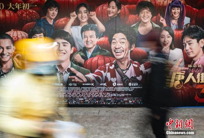 资料图：行人经过位于北京市朝阳区望京地区的一家电影院的户外广告。中新社记者 侯宇 摄