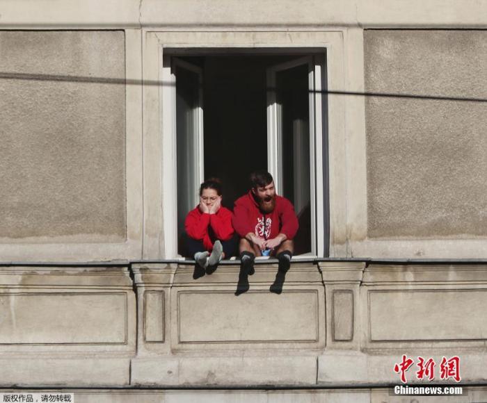 资料图：波兰华沙，一对夫妇坐在五层楼高的窗台上晒太阳。