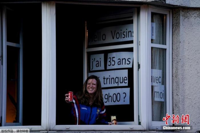 比利时布鲁塞尔，一名女士在窗户前举起饮料庆祝生日。