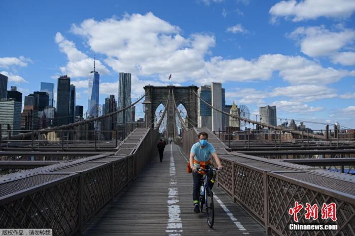 戴着口罩的骑手在纽约布鲁克林大桥上骑行。