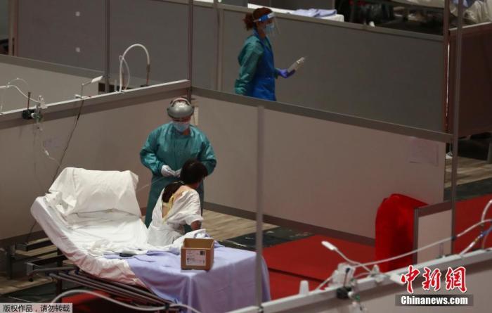 西班牙马德里会展中心“方舱医院”内，医护人员在与患者交流。