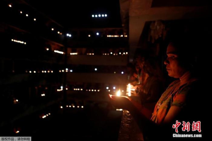 当地时间4月5日21点，印度民众熄灯9分钟，点燃蜡烛和油灯为抗疫祈福。图为孟买民众在阳台上捧起烛光。
