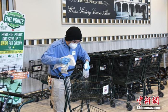 当地时间4月6日，在位于大华府地区的一家超市里，工作人员给每一个推车用酒精消毒。<em></em>
中新社记者 沙晗汀 摄