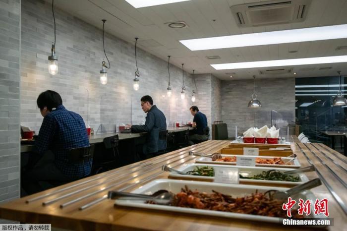 当地时间4月9日，位于韩国首尔的一家公司员工正在用餐，该公司为了保证员工的就餐安全，在自助餐区设置了玻璃罩。