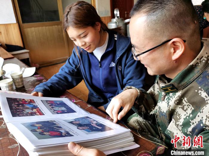 4月11日，武警青海总队玉树支队官兵到藏族女生才文拉毛家回访，翻看此前包括才文拉毛和弟弟在内的十名孤儿与武警官兵相处的照片。<em></em>
中新社记者 张添福 摄