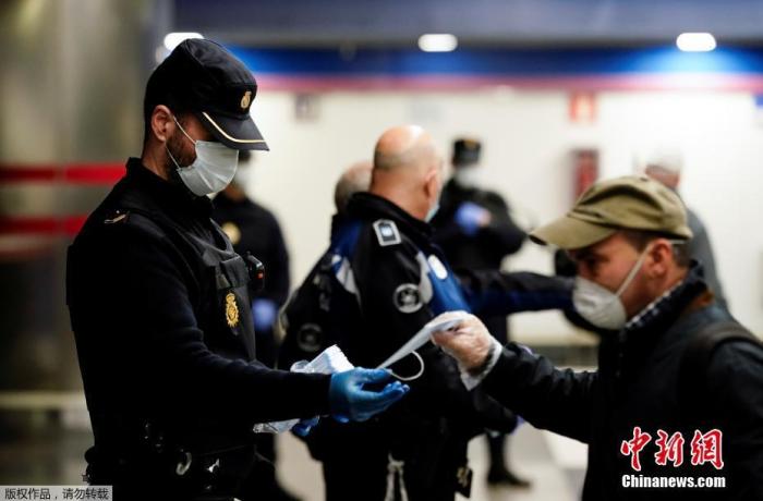 当地时间4月13日，西班牙马德里，警察在地铁站向民众分发免费的防护口罩。