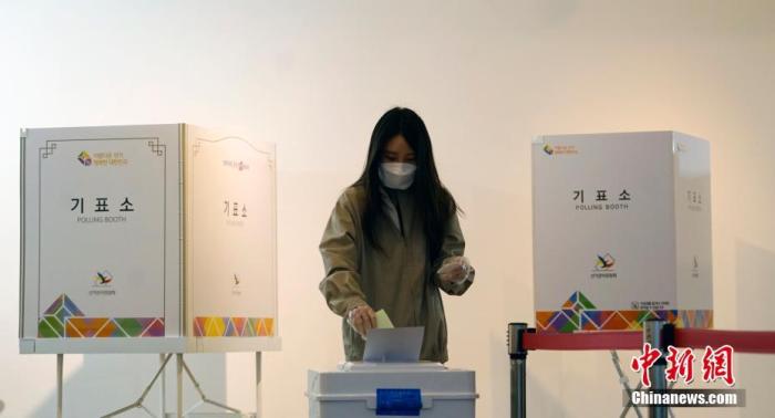 当地时间4月15日，韩国在疫情“红色预警”中启动第21届国会选举。投票站采取强力防控措施，对数万名居家隔离者等单独设置投票时间。图为在韩国首尔一投票站，市民戴口罩和手套投票。 中新社记者 曾鼐 摄