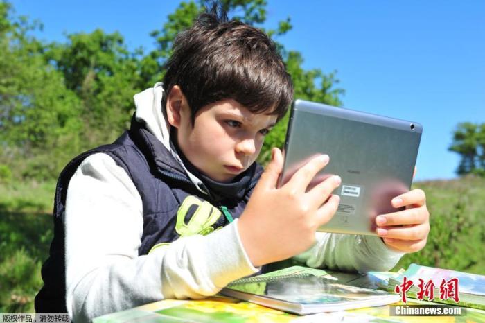 资料图：意大利男孩在山上通过平板电脑在线上课。