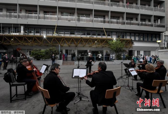 当地时间4月20日，新冠肺炎疫情期间，希腊雅典福音医院的医务人员在院子里聆听希腊国家广播交响乐团的音乐会。