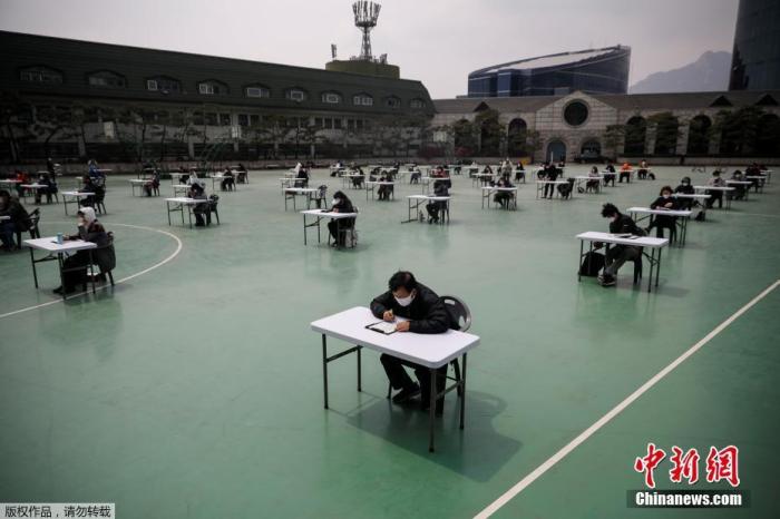 当地时间4月25日，韩国为了避免新型冠状病毒传播，在露天操场为求职者举行入职考试。图为考生在答题中。
