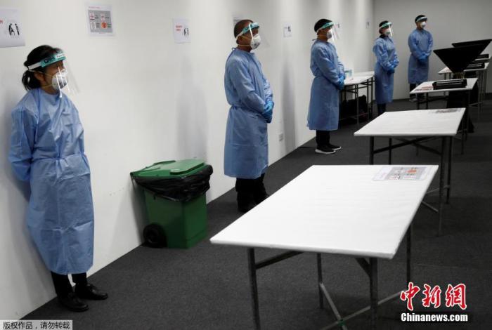 新加坡樟宜展览中心被改建成“方舱医院”，工作人员穿好防护服在接待区等待病人入院。
