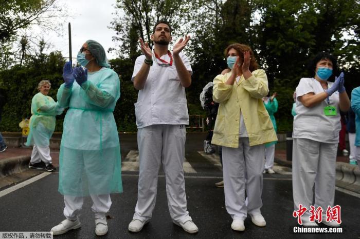 当地时间4月27日，在西班牙马德里的一家医院外，医护人员在为全国禁闭期间居家隔离的民众们鼓掌欢呼，为他们加油打气。