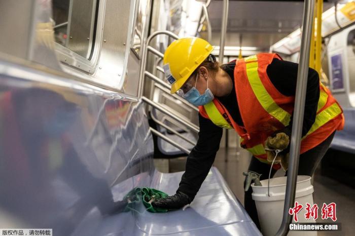 当地时间5月6日，纽约地铁工作人员在车厢内外进行清理消毒工作。