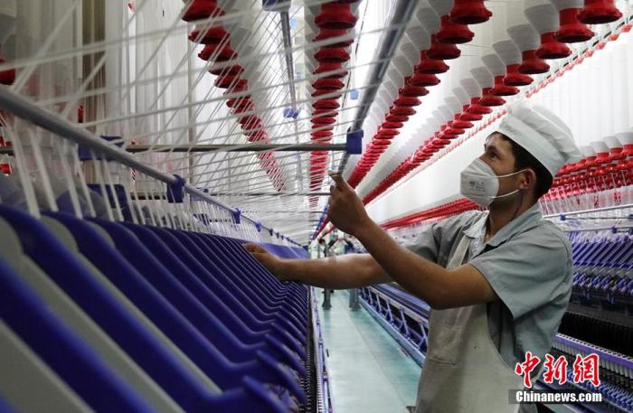 资料图：纺织企业员工正进行生产工序作业。 确·胡热 摄
